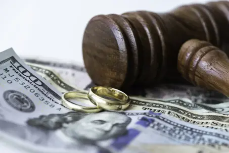 Wedding rings and gavel on American dollar bills.